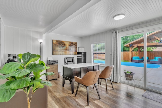 office with a wealth of natural light, light wood-type flooring, and beamed ceiling