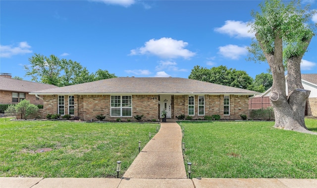 single story home with a front yard, a shingled roof, and brick siding