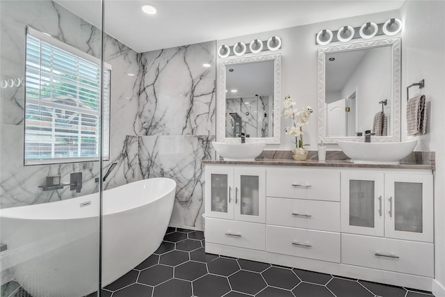 full bathroom with a freestanding tub, double vanity, tile patterned flooring, and a sink