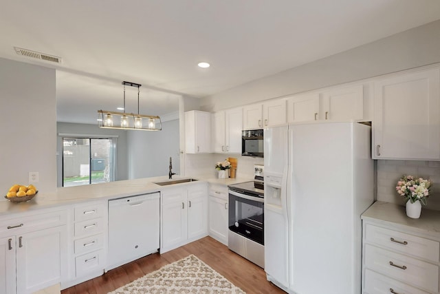 kitchen with tasteful backsplash, visible vents, white appliances, and a sink