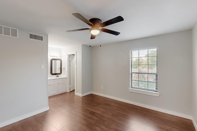 unfurnished room with a ceiling fan, visible vents, and dark wood-type flooring