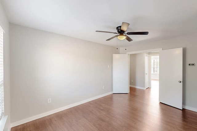 empty room with baseboards, wood finished floors, and ceiling fan