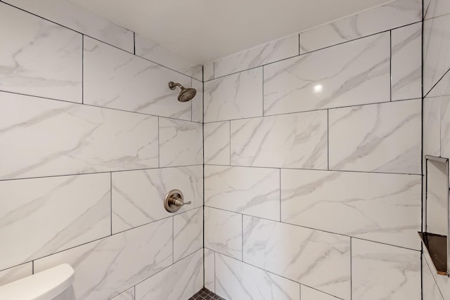 bathroom featuring toilet and a tile shower