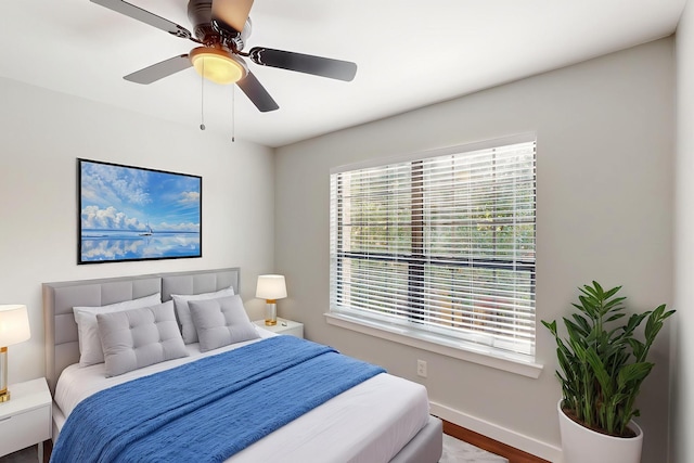 bedroom featuring wood finished floors, a ceiling fan, and baseboards