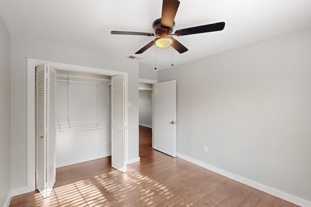 unfurnished bedroom featuring a closet, visible vents, wood finished floors, and baseboards