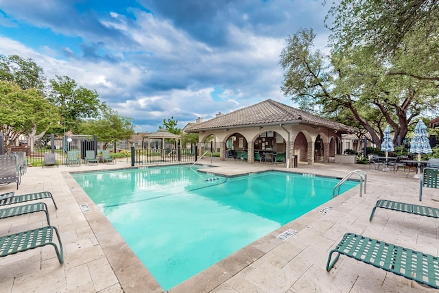 community pool featuring fence, a gazebo, and a patio area