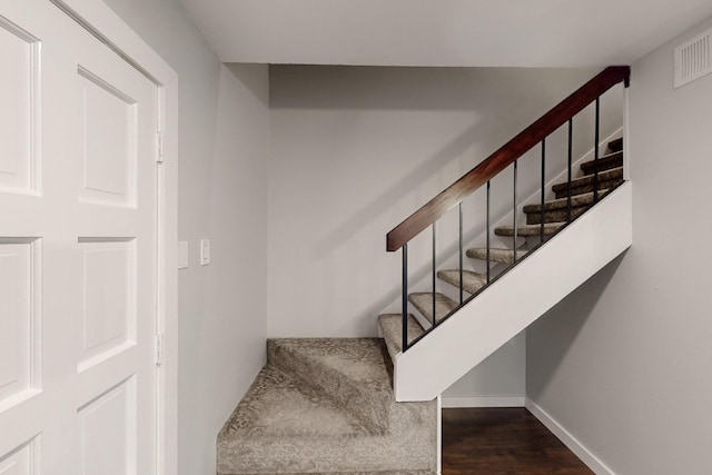 stairs with visible vents, wood finished floors, and baseboards