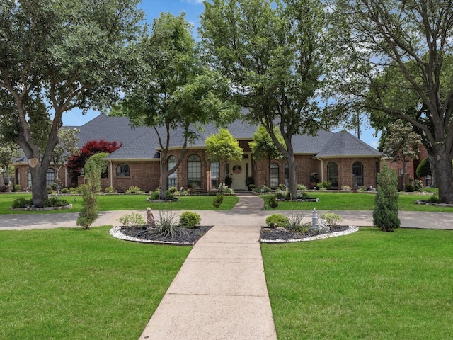 view of front of property featuring brick siding, roof with shingles, and a front yard