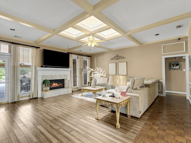 living area with a ceiling fan, visible vents, a fireplace, baseboards, and coffered ceiling