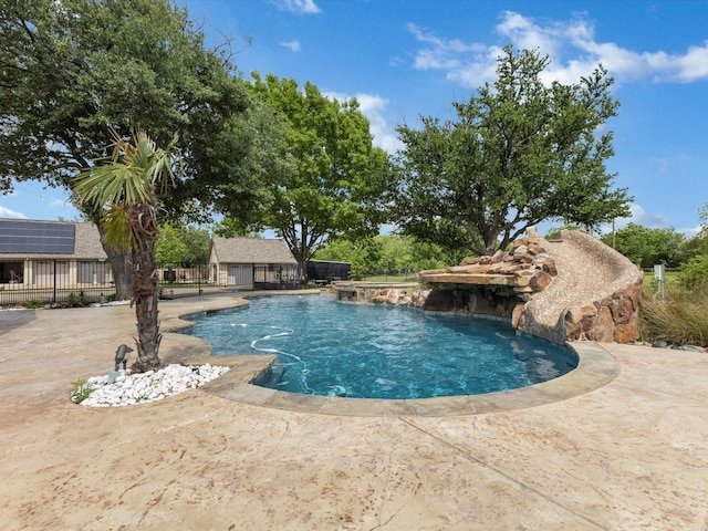 view of pool with fence, a fenced in pool, an outbuilding, and a patio