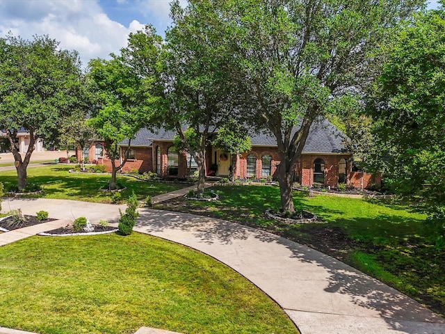 view of front of home with brick siding, roof with shingles, and a front yard