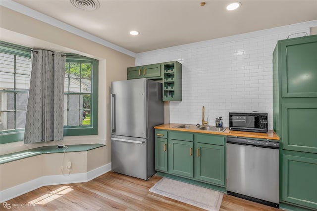 kitchen featuring stainless steel appliances, green cabinets, a sink, light wood-type flooring, and wooden counters