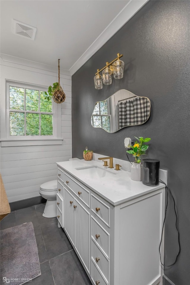 full bath featuring healthy amount of natural light, toilet, vanity, tile patterned floors, and ornamental molding