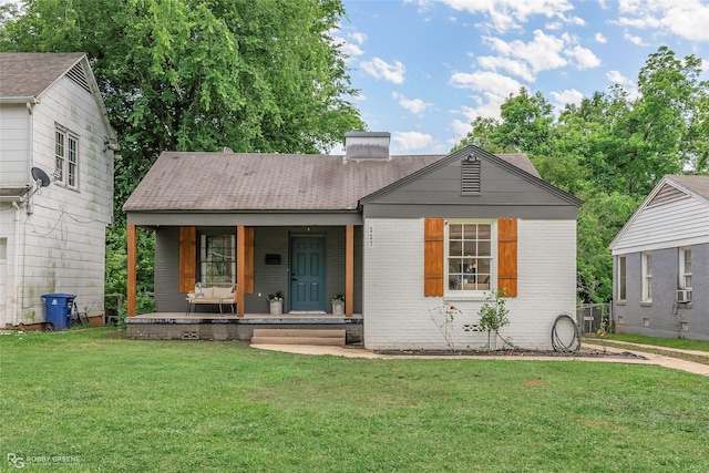 view of front of property featuring a front yard, a porch, brick siding, and roof with shingles