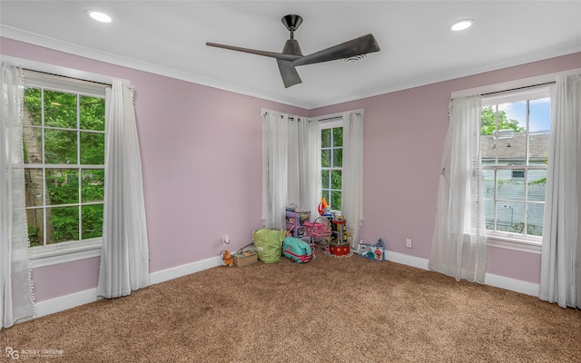 playroom with carpet floors, healthy amount of natural light, baseboards, crown molding, and a ceiling fan