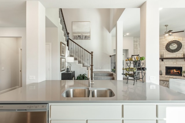 1009 Canuela Way, Justin, TX 76247 - kitchen with a ceiling fan, a stone fireplace, white cabinetry, stainless steel dishwasher, and open floor plan