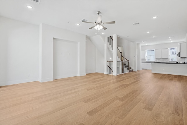 unfurnished living room with visible vents, recessed lighting, light wood finished floors, and stairs