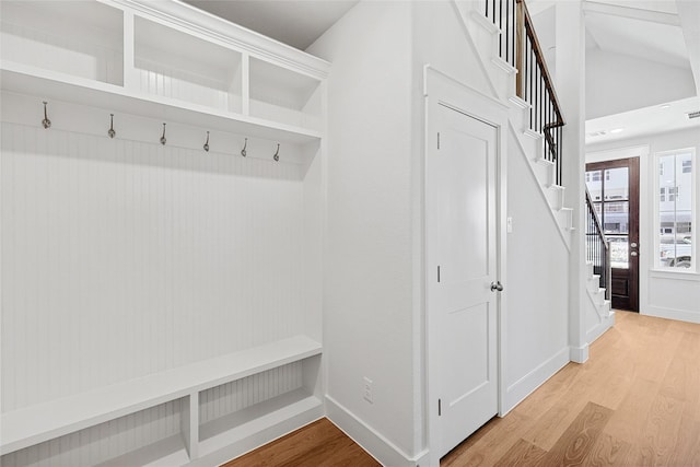 mudroom with lofted ceiling, light wood finished floors, and baseboards