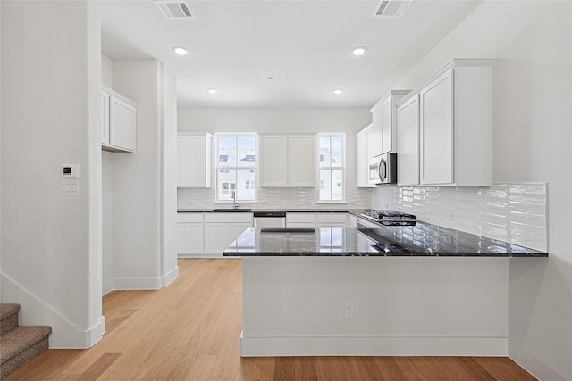 kitchen featuring appliances with stainless steel finishes, visible vents, dark stone countertops, and baseboards