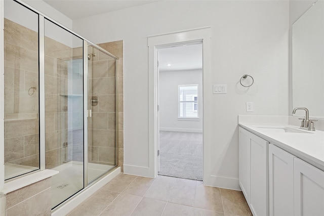 full bath featuring a stall shower, vanity, tile patterned floors, and baseboards
