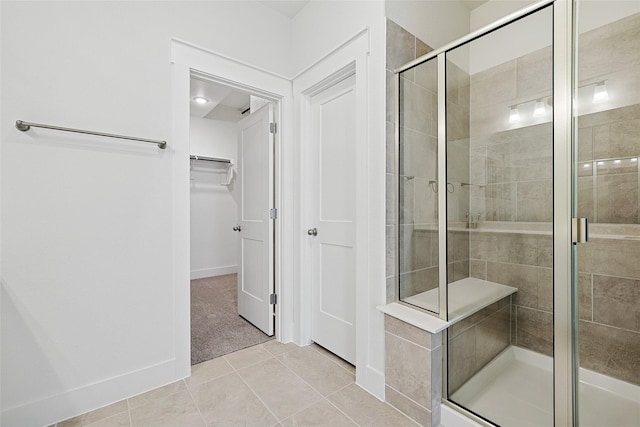 bathroom with a stall shower, tile patterned flooring, and a spacious closet