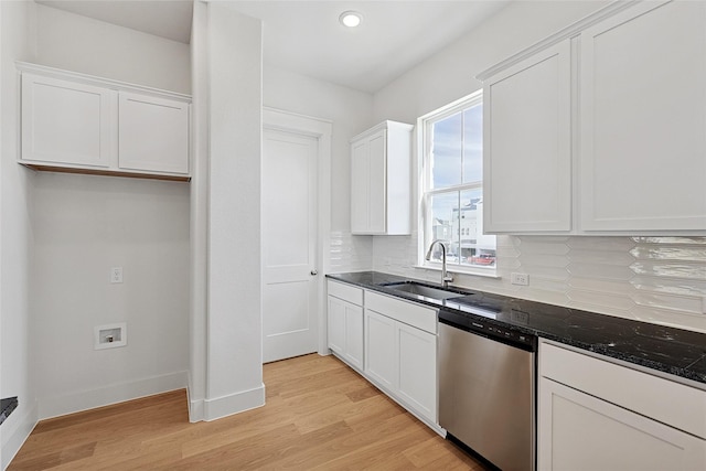 kitchen with white cabinetry, stainless steel dishwasher, light wood-style flooring, a sink, and backsplash