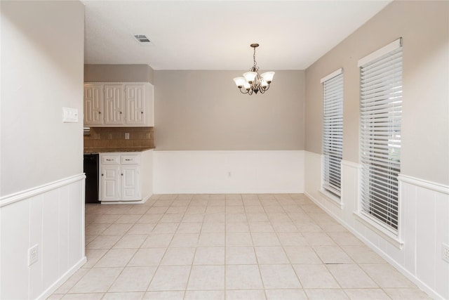 unfurnished dining area with visible vents, light tile patterned floors, and a notable chandelier