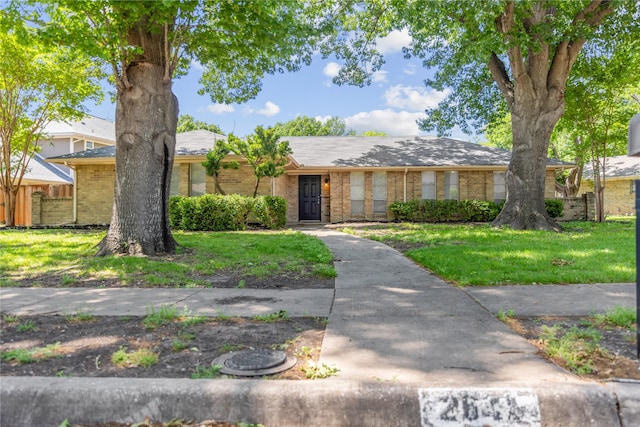 ranch-style house with a front yard, fence, and brick siding