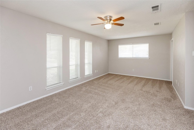 unfurnished room with a ceiling fan, visible vents, carpet, and baseboards