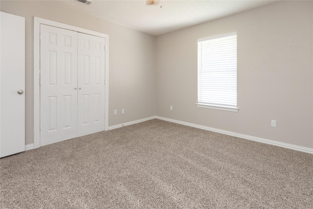 unfurnished bedroom with visible vents, a closet, baseboards, carpet floors, and a ceiling fan