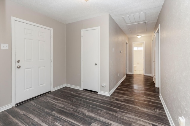 interior space with baseboards, visible vents, a textured ceiling, and dark wood-type flooring