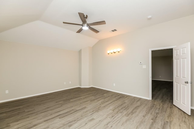 spare room with ceiling fan, light wood-type flooring, vaulted ceiling, and baseboards