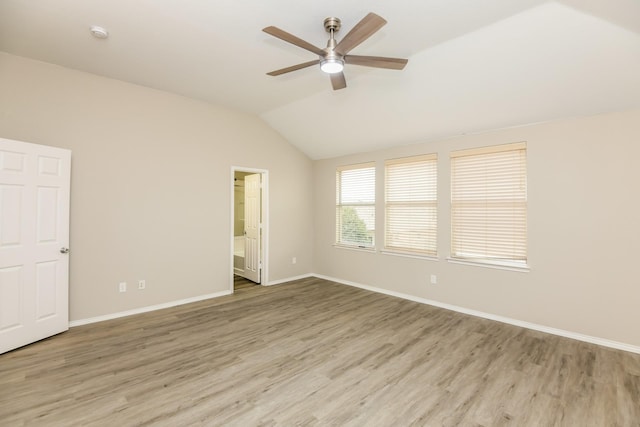 empty room with a ceiling fan, vaulted ceiling, wood finished floors, and baseboards