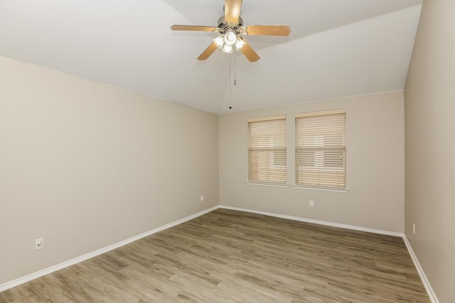 empty room with light wood-style floors, ceiling fan, vaulted ceiling, and baseboards