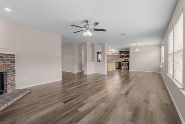 13140 Fencerow Rd, Fort Worth, TX 76244 - unfurnished living room with ceiling fan with notable chandelier, baseboards, a brick fireplace, and dark wood-type flooring
