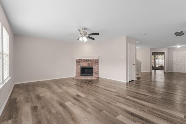 13140 Fencerow Rd, Fort Worth, TX 76244 - unfurnished living room with a brick fireplace, a ceiling fan, wood finished floors, and visible vents