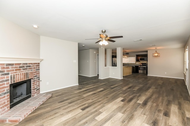 unfurnished living room featuring ceiling fan, visible vents, dark wood-style floors, baseboards, and a fireplace