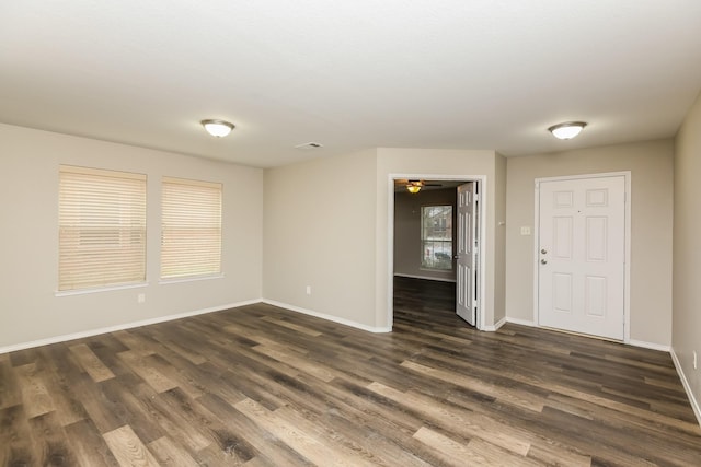 spare room featuring baseboards, visible vents, ceiling fan, and dark wood-style flooring