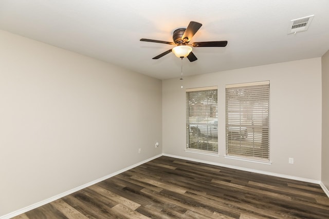 spare room with a ceiling fan, visible vents, baseboards, and dark wood finished floors