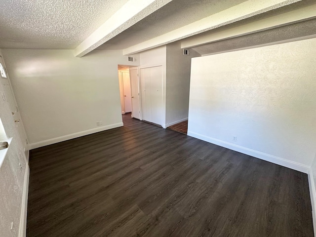 unfurnished room with dark wood finished floors, baseboards, visible vents, and a textured ceiling