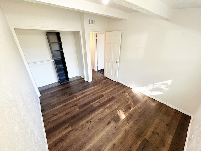 unfurnished bedroom featuring a closet, visible vents, baseboards, and dark wood finished floors