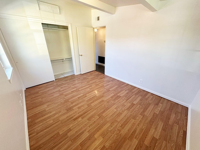 unfurnished bedroom featuring baseboards, visible vents, wood finished floors, and a closet