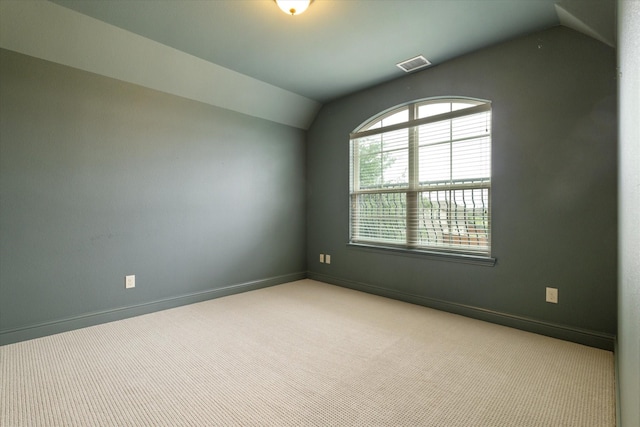 carpeted empty room featuring baseboards, visible vents, and vaulted ceiling