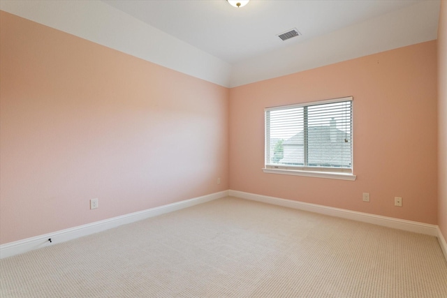 empty room featuring baseboards, light carpet, and visible vents