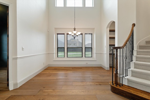 unfurnished dining area featuring light wood-type flooring, a chandelier, a healthy amount of sunlight, and stairway