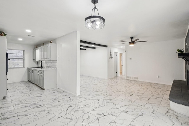 kitchen with light countertops, a sink, baseboards, visible vents, and a ceiling fan