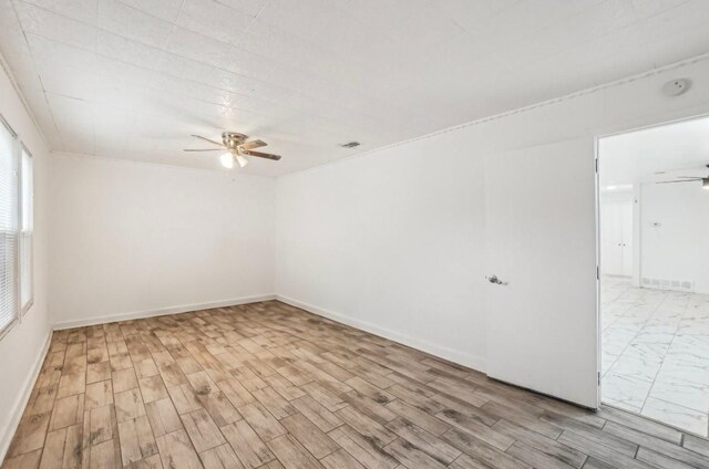 empty room featuring wood finished floors, a ceiling fan, visible vents, and baseboards