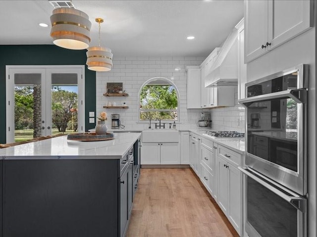 8313 Jonquil Dr, Waco, TX 76708 - kitchen with white cabinetry, tasteful backsplash, a sink, light wood finished floors, and appliances with stainless steel finishes