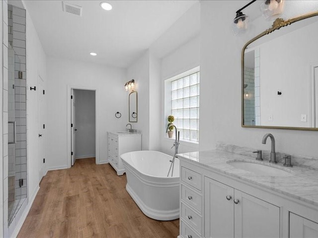 8313 Jonquil Dr, Waco, TX 76708 - full bath with visible vents, wood finished floors, a freestanding bath, two vanities, and a sink