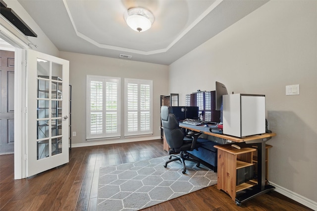 office featuring baseboards, a tray ceiling, hardwood / wood-style flooring, and visible vents